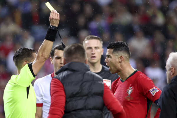 Rozhodca Donatas Rumsas (vľavo) ukazuje žltú kartu portugalskému hráčovi Cristianovi Ronaldovi.